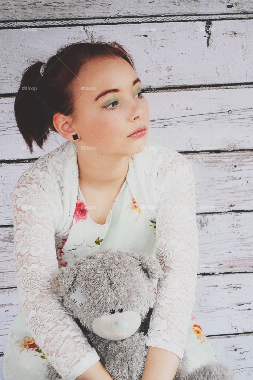 Young woman sitting on bench with teddy bear