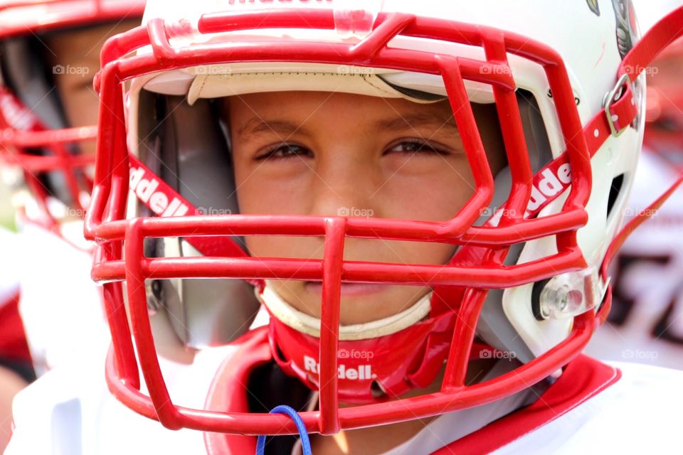 Boy with game face wearing red football helmet during tackle football game