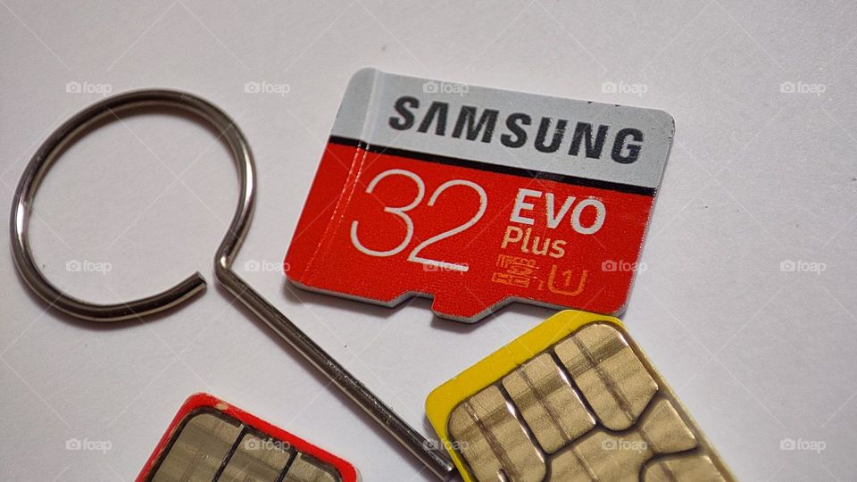 Sim ejection tool with Samsung 32gb Evo Plus memory card and sim cards with metal surface