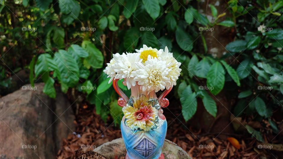 Beautiful white flowers in a colourful flowerpot with a flower sculpture, Flowers in a vase, colourful vase, white flowers in a vase