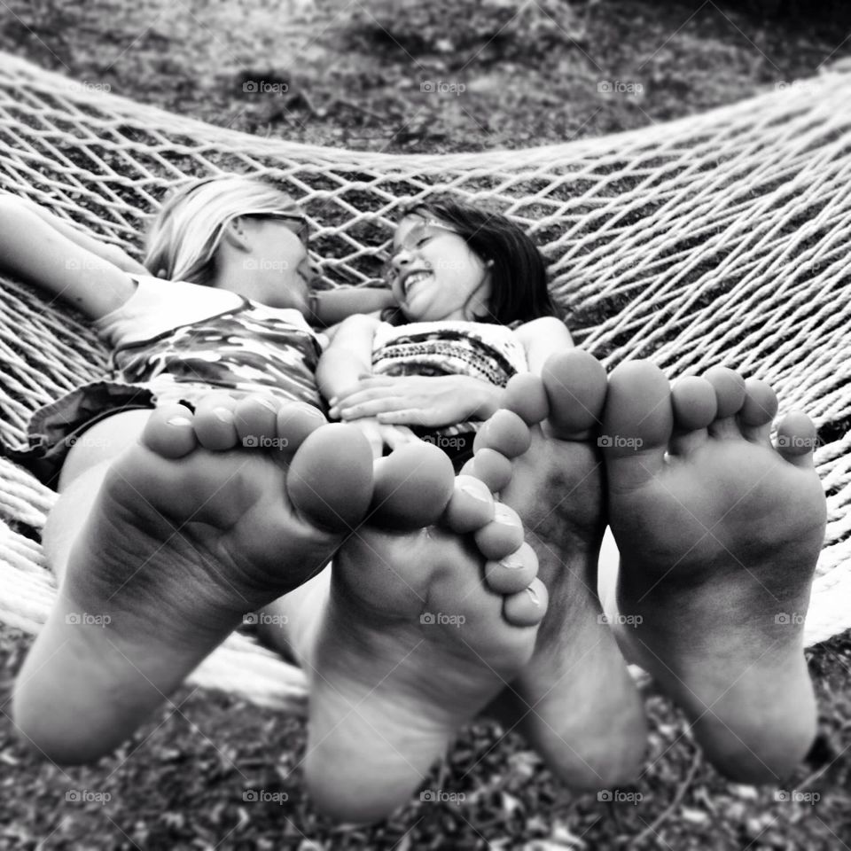 Friendship. Bare feet foreground of two girls in hammock