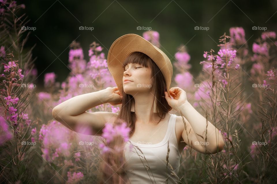 Beautiful young woman in a field of blossom flowers in boho style