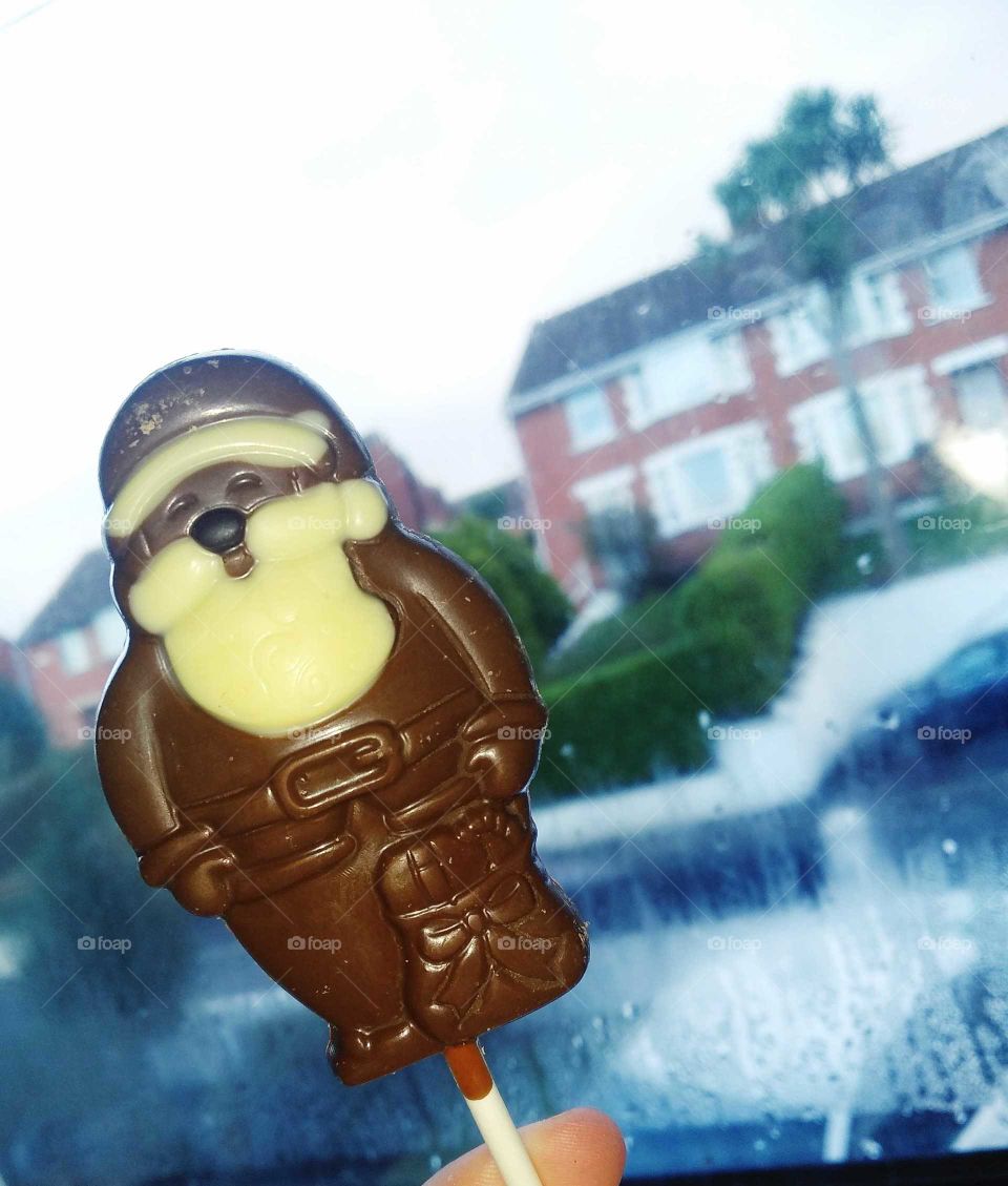 dark, milk and white chocolate lolly in front of a bright, dewy window