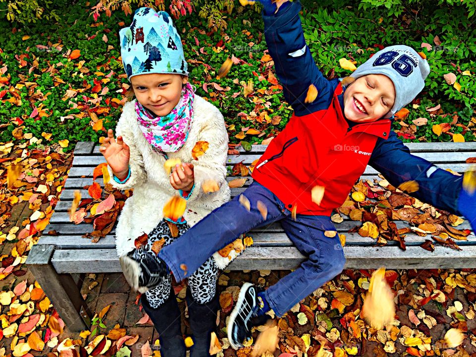 Happy brother and sister sitting on bench in park