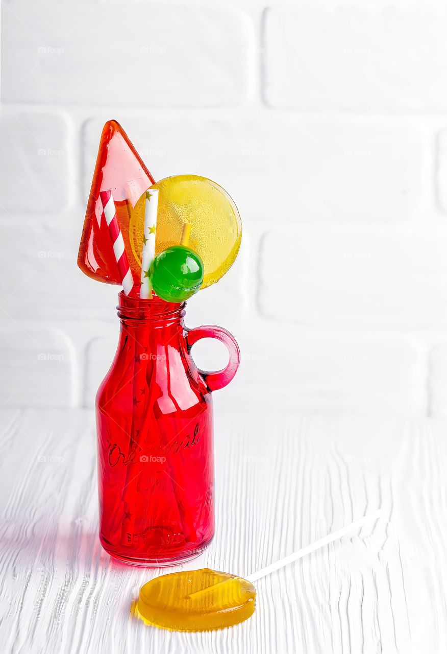 Close up of a variety of lollipops and candies on white brick wall background