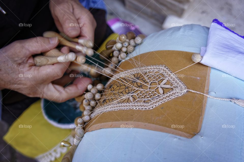 Close-up of a person's hand lacing pillow