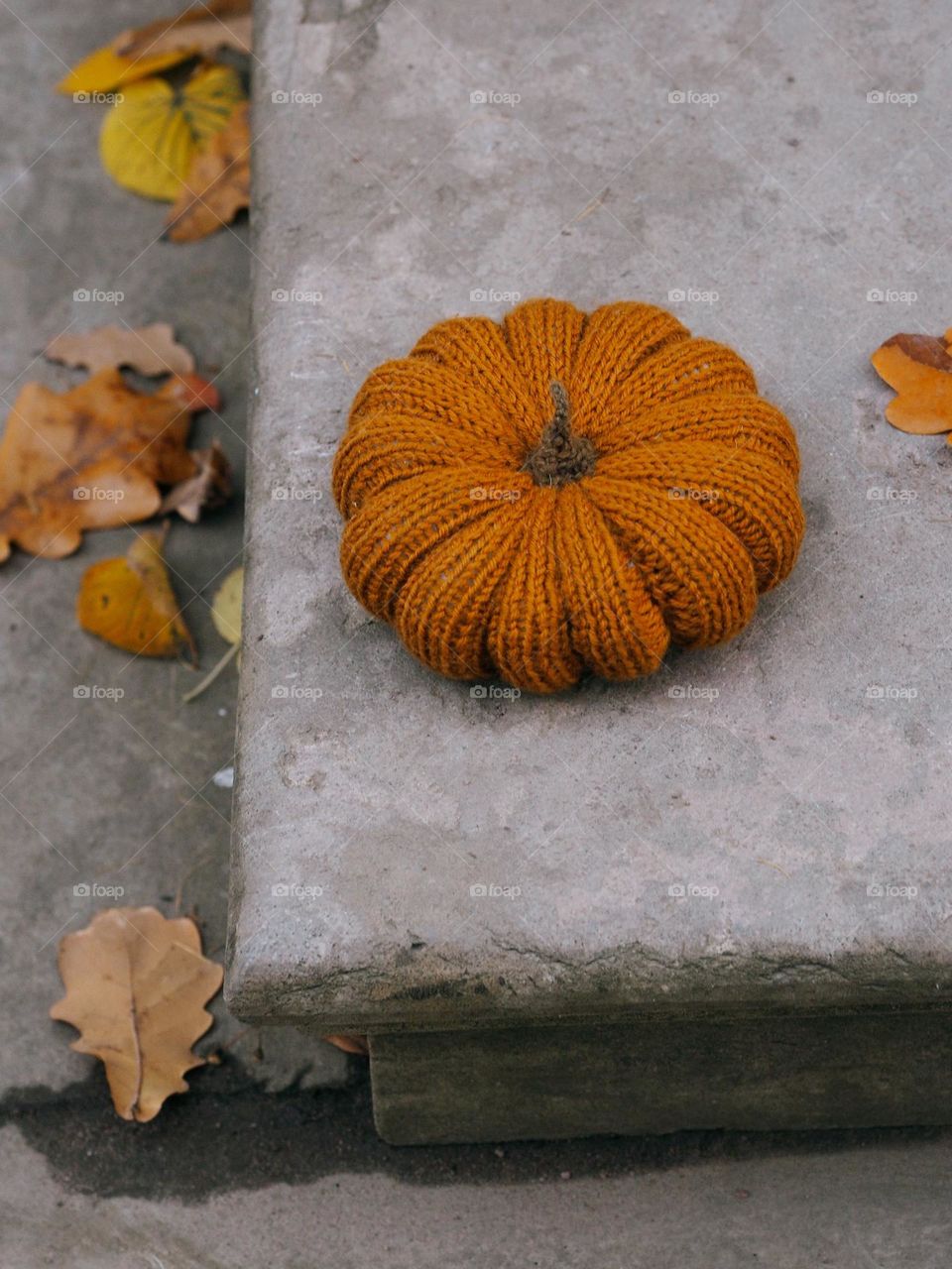 Crocheted orange pumpkin on a concrete background on an autumn day, autumn, Halloween concept 