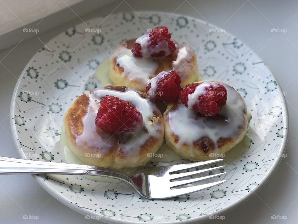 Cottage cheese pancake with raspberry on a plate.