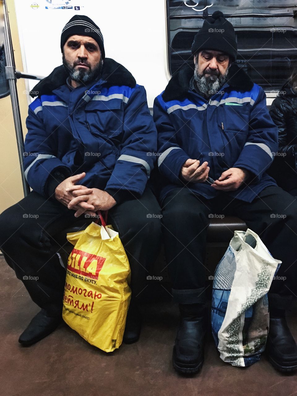 Two arabic guys are sitting in subway in subway services uniform