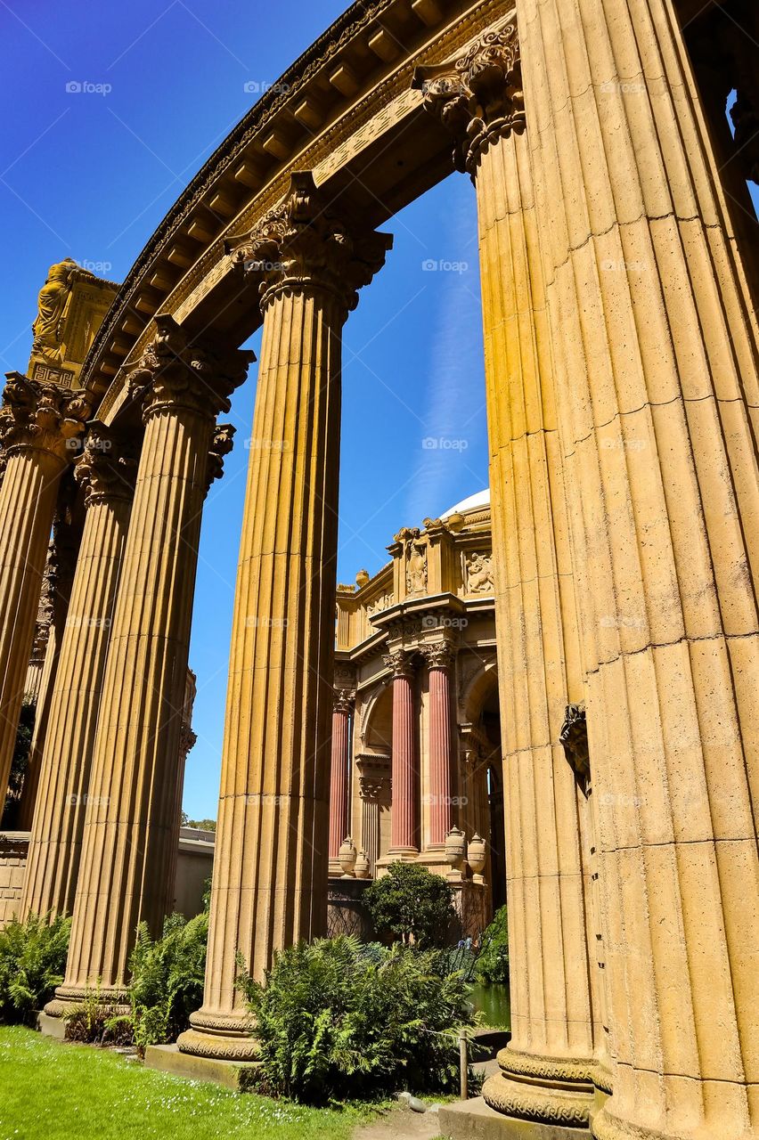 Architectural view through the columns of the palace of fine arts in San Francisco California showing the Greco Roman style architecture and the lagoon