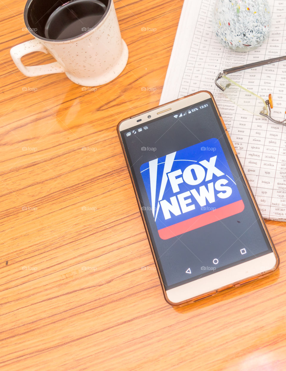 Kolkata, India, February 3, 2019: Fox news app (application) visible on mobile phone screen beautifully placed over a wooden table with a newspaper and a cup of coffee. A Technology Product Shoot.