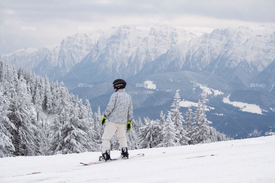 Young man snowboarding in peak Postavarul 