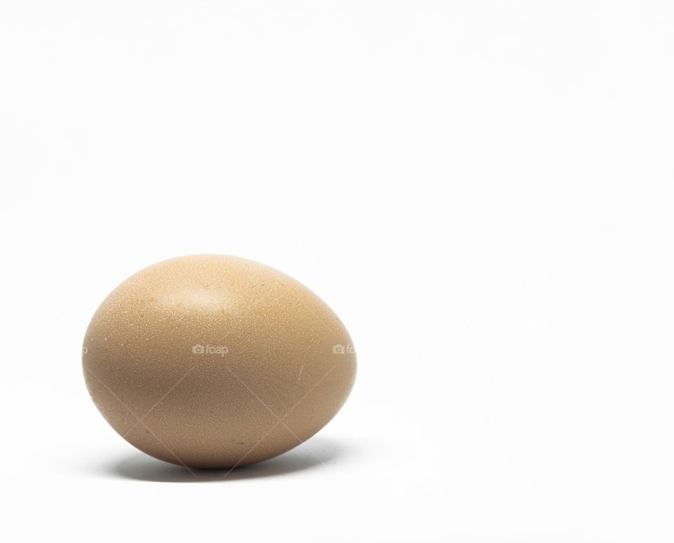 A faintly speckled chicken egg on a white background 