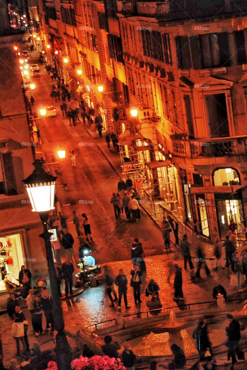Night shoppers in Rome. Street lamps glow above Bustling streets at night near the Spanish steps in Rome