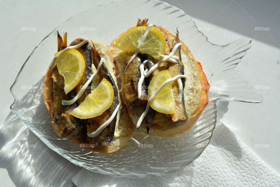 sandwiches with sprats and lemon on a plate