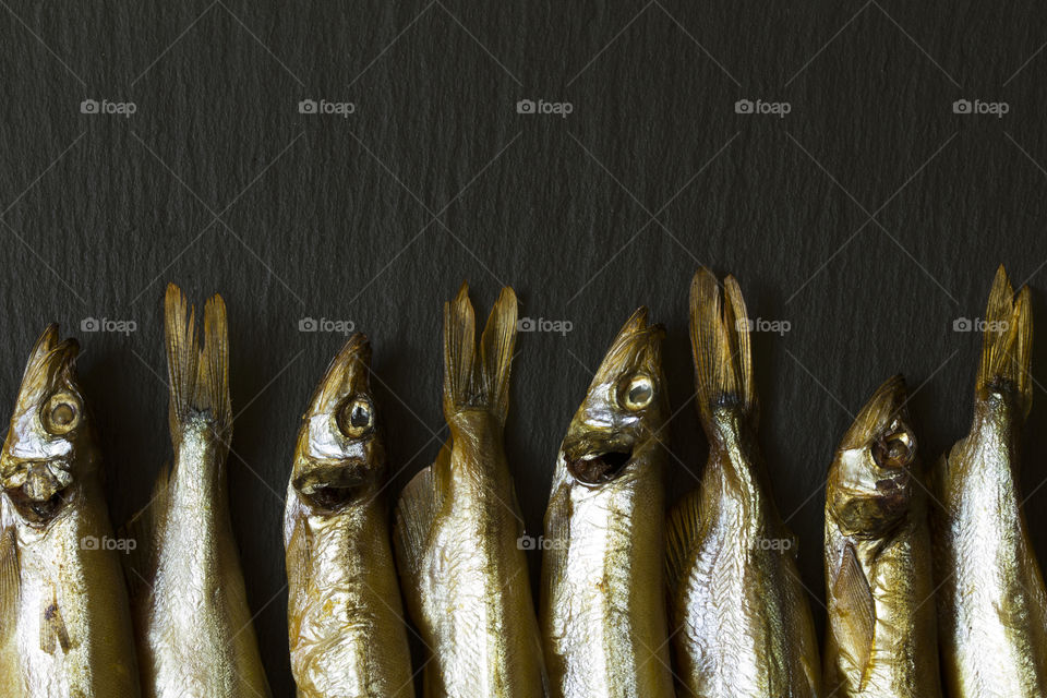 Smoked fish. Little smoked fish, 
capelinlies on a slate stone Board with copy space.