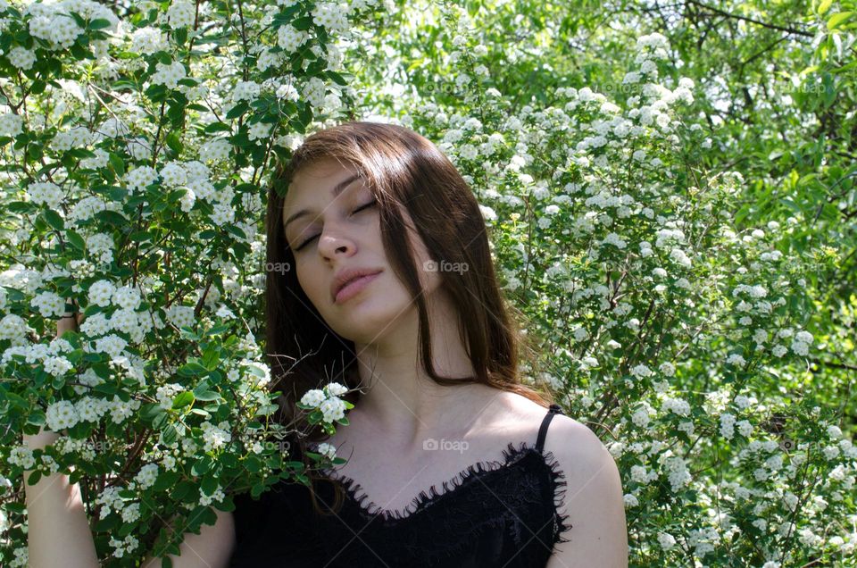 Portrait of a Beautiful Young Girl on Background of Flowers