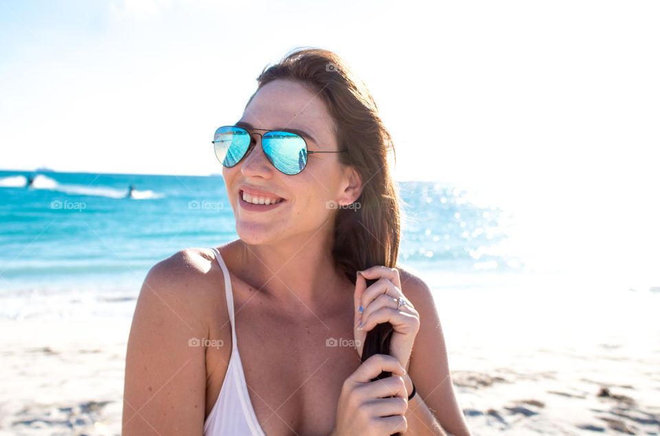 Close up of woman smiling on the beach in blue sunglasses