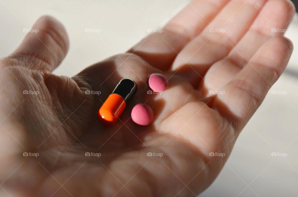 vitamins capsules and pills dose colour in hand close up background