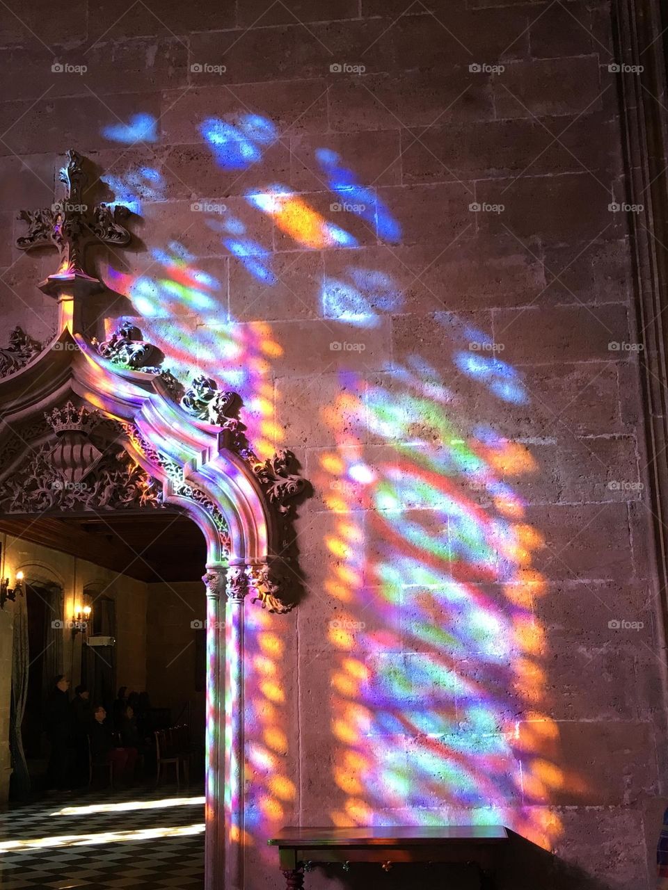 Stained glass reflection on stone church interior.
