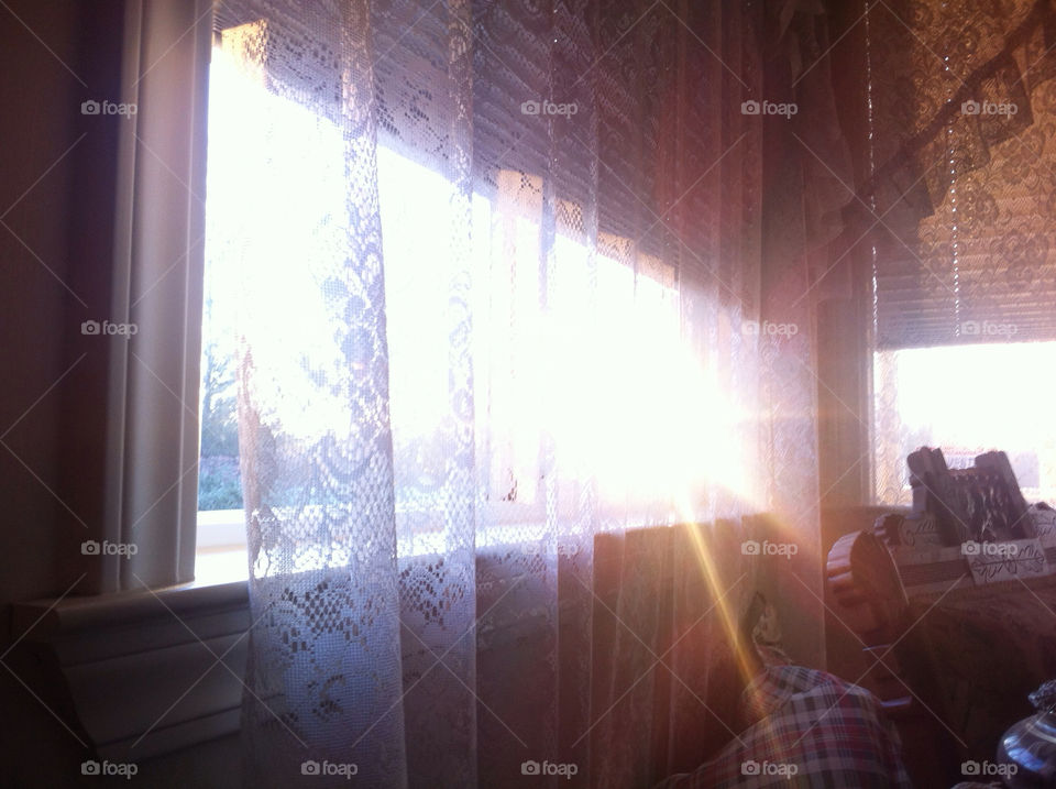 A view of the sunrise through a lace curtain.