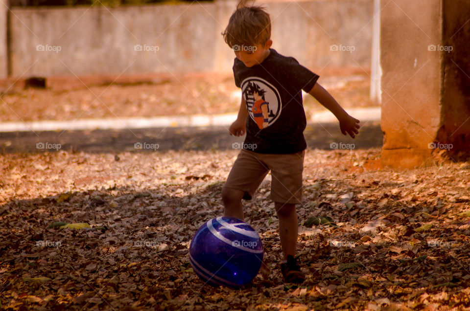 blond boy playing ball on the farm
