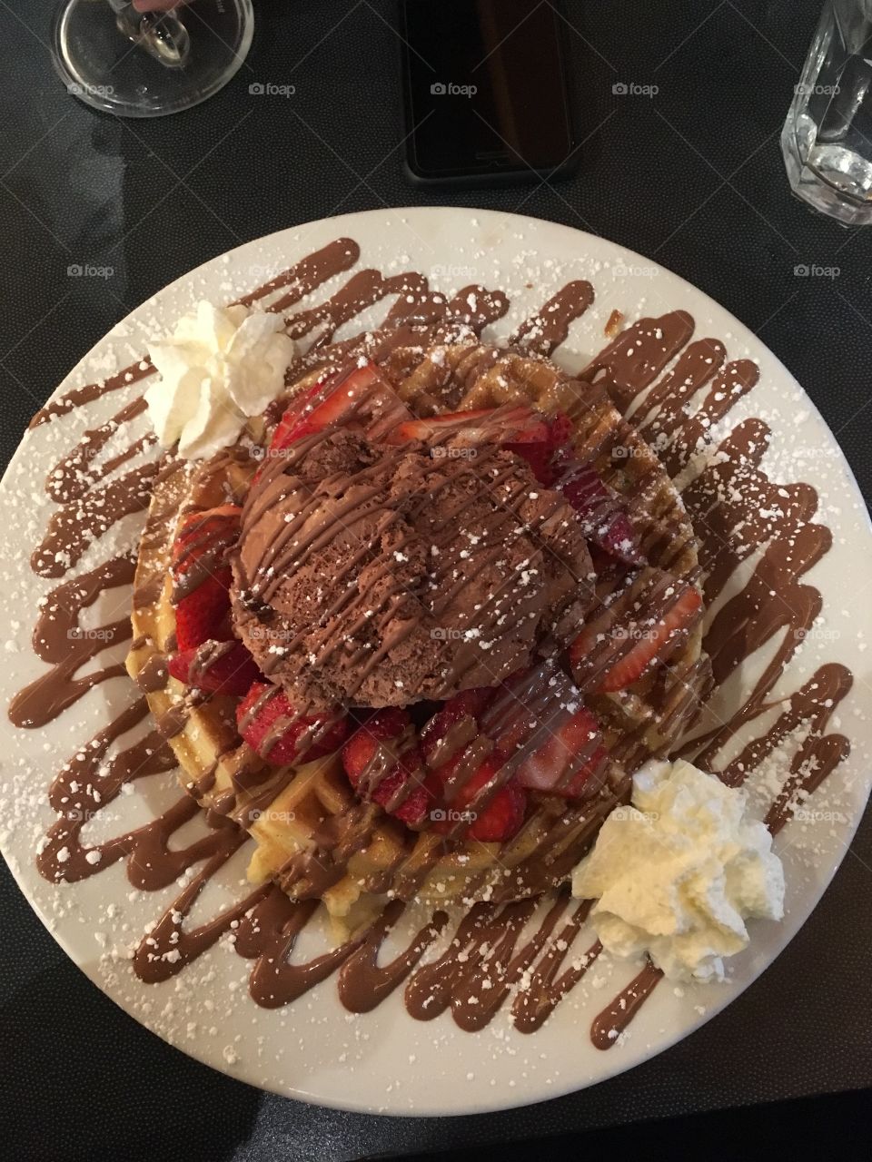 A delicious Nutella waffle accompanied with strawberries and whipped cream.