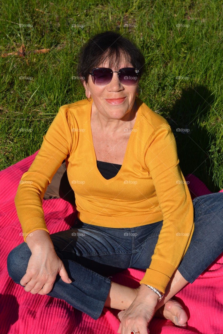 woman smiling and relaxing on a blanket in green grass