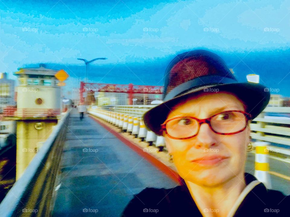 A self portrait with the car lane of the street leading across the Pulaski Bridge from LIC, Queens to Greenpoint, Bklyn, NY in the background photographed on a lovely Spring afternoon in 2019. Hypnotic Productions