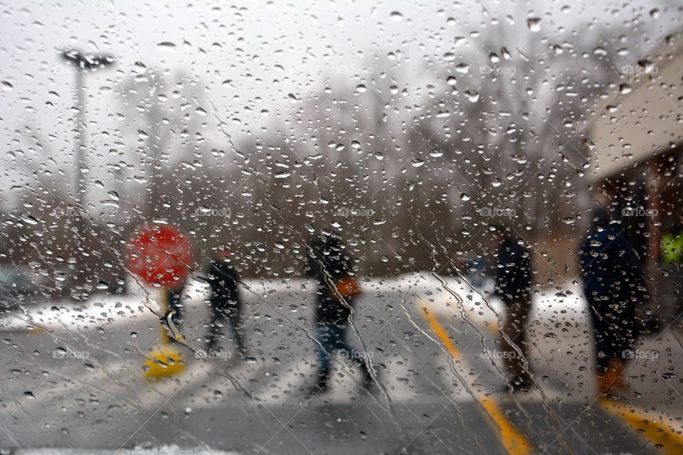 People rushing across the street during a rainstorm 