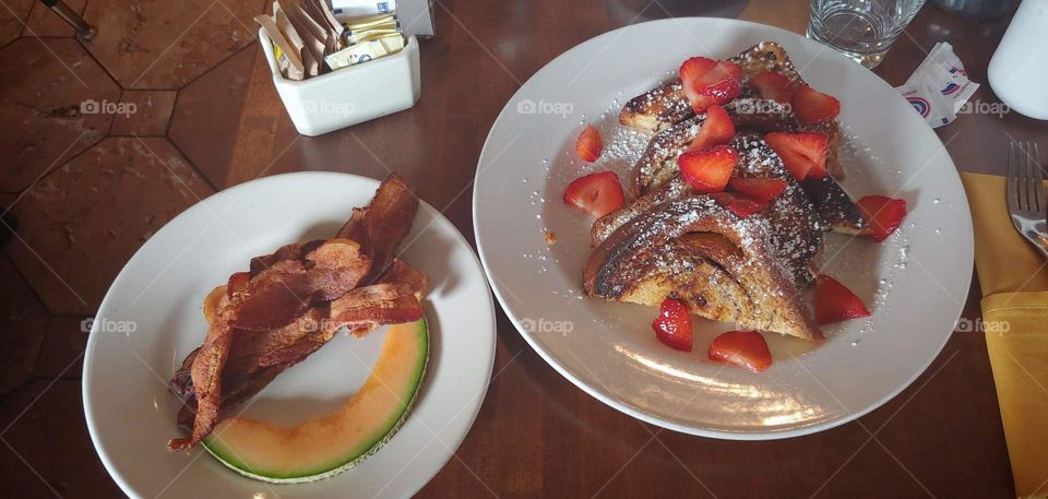 Delicious Morning Breakfast. Mouth Watering Strawberries and Cantaloupe with Perfectly Crisped Bacon and French Toast Raisin Bread.