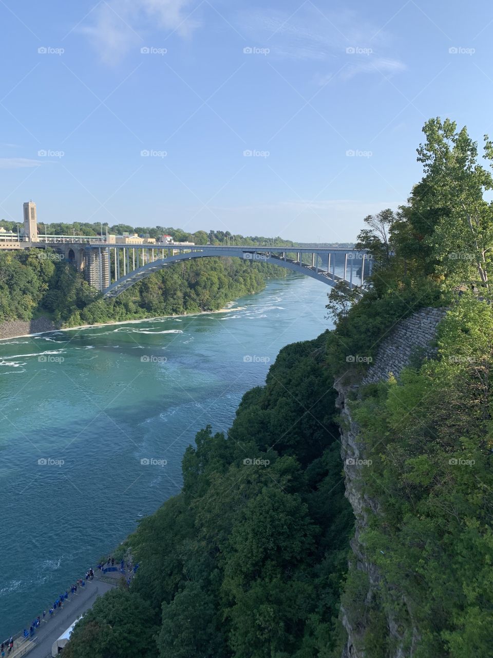 Clear water under a bridge with a slight angle with sharp colors. The green and blue interact well with each other with an interlaced silver being the bridge.