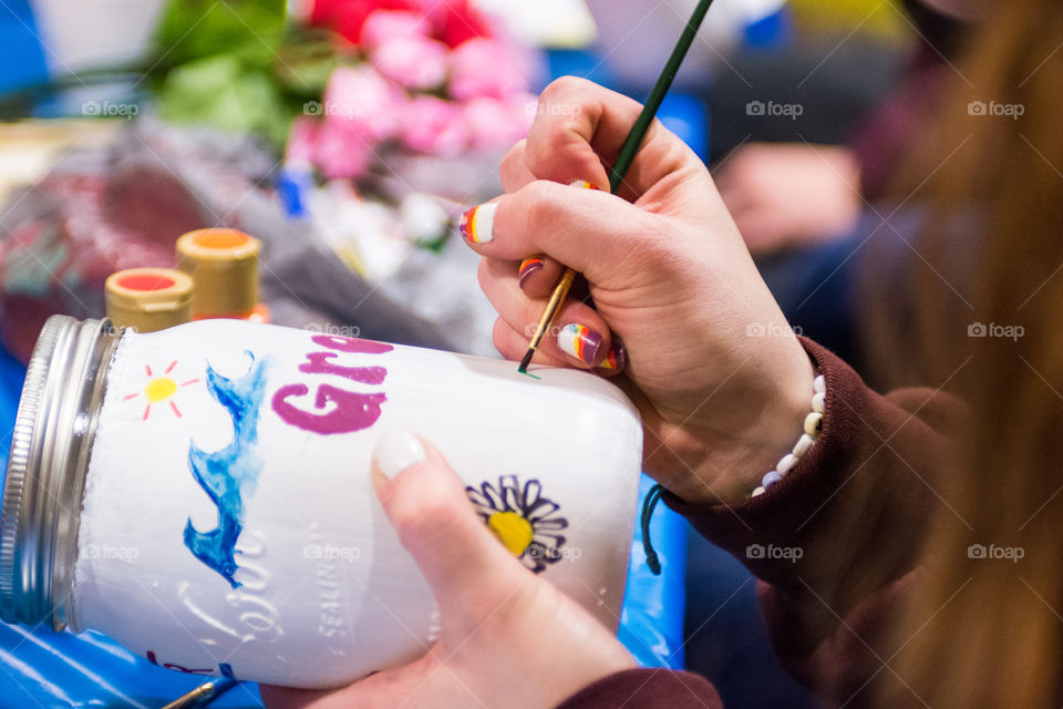 A girl paints a jar with vibrant colors while crafting 