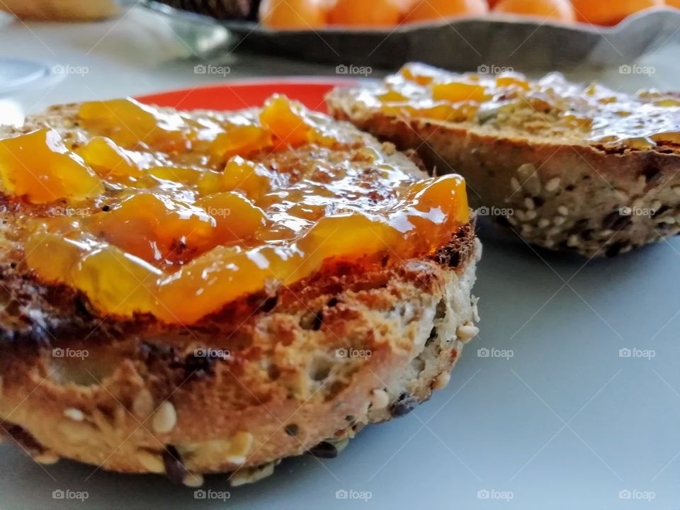 Homemade peach jam spread on whole grain dark rye bread