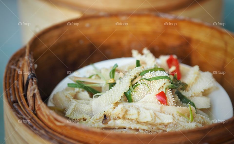 Tripe braised with chilli and shallots (scallions). A popular food item in yum cha or dim sum line up. The tripe has a soft yet crunchy consistency or mouthfeel. The dish is kept warm inside a bamboo steamer.