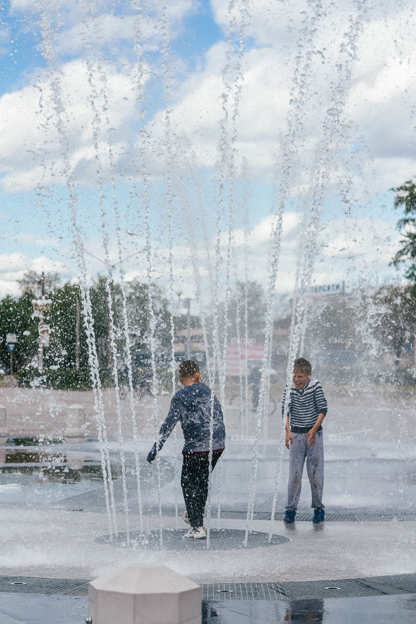 boys dabble in the fountain in the summer