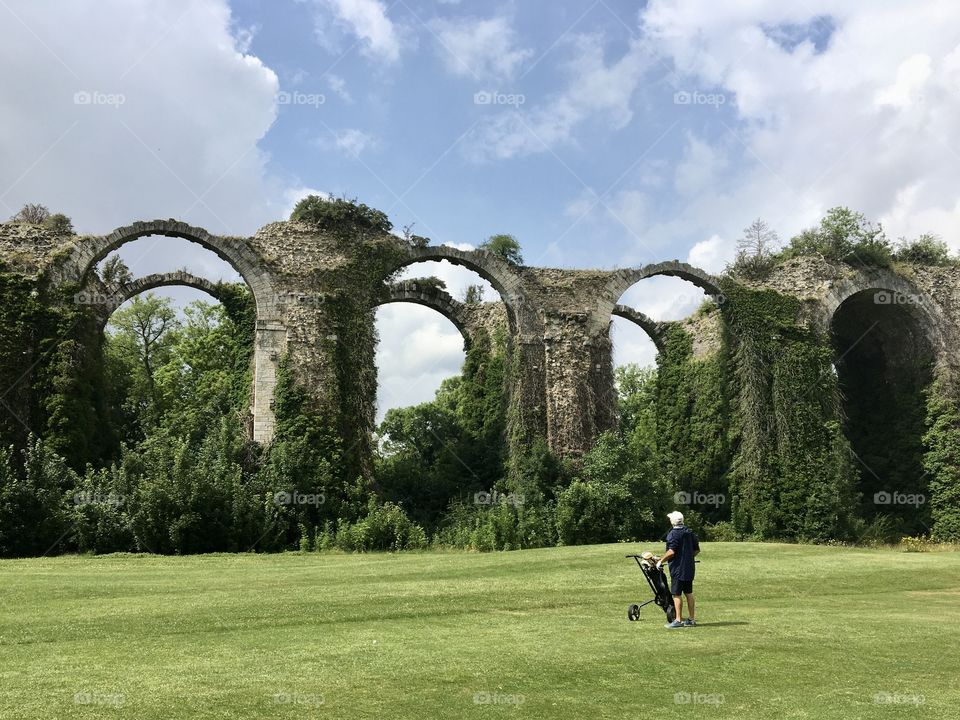 Playing golf near historic ruins of aqueduct 