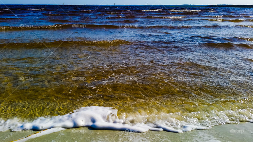 lake merge with the skyline, waves forming foam at the shore.