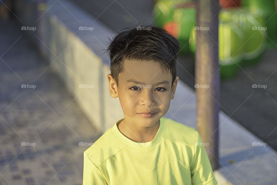 Portrait of a young boy wearing a green t-shirt standing smiling.