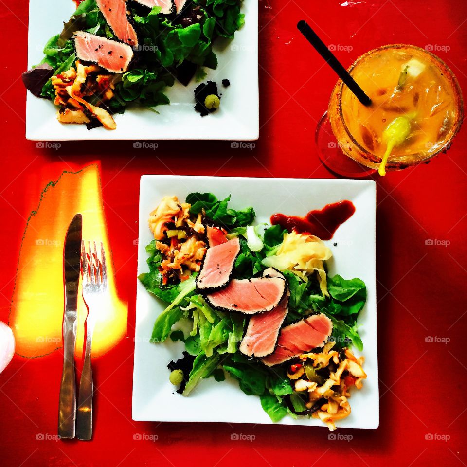 Tropical eats. Seared tuna salads and a Bloody Mary on a red table