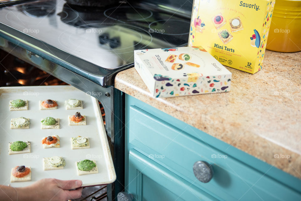 Person placing a baking sheet with tarts in the oven 