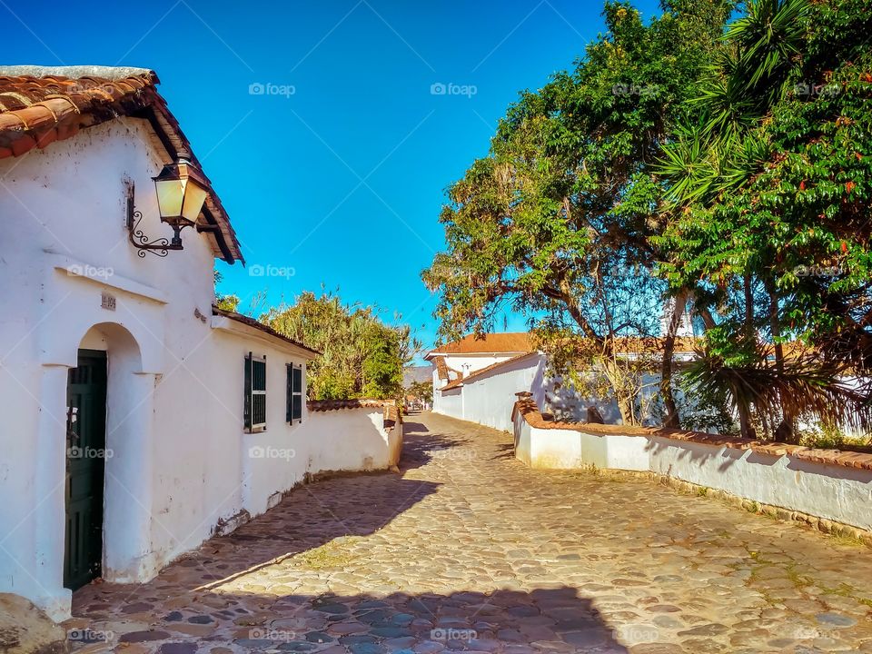 Calle empedrada de Villa de Leyva, Boyacá, Colombia en una mañana soleada y de cielo azul. Arquitectura colonial. Cobbled street in Villa de Leyva, Boyacá, Colombia on a sunny morning with blue sky. Colonial architecture. Horizontal. Street photo