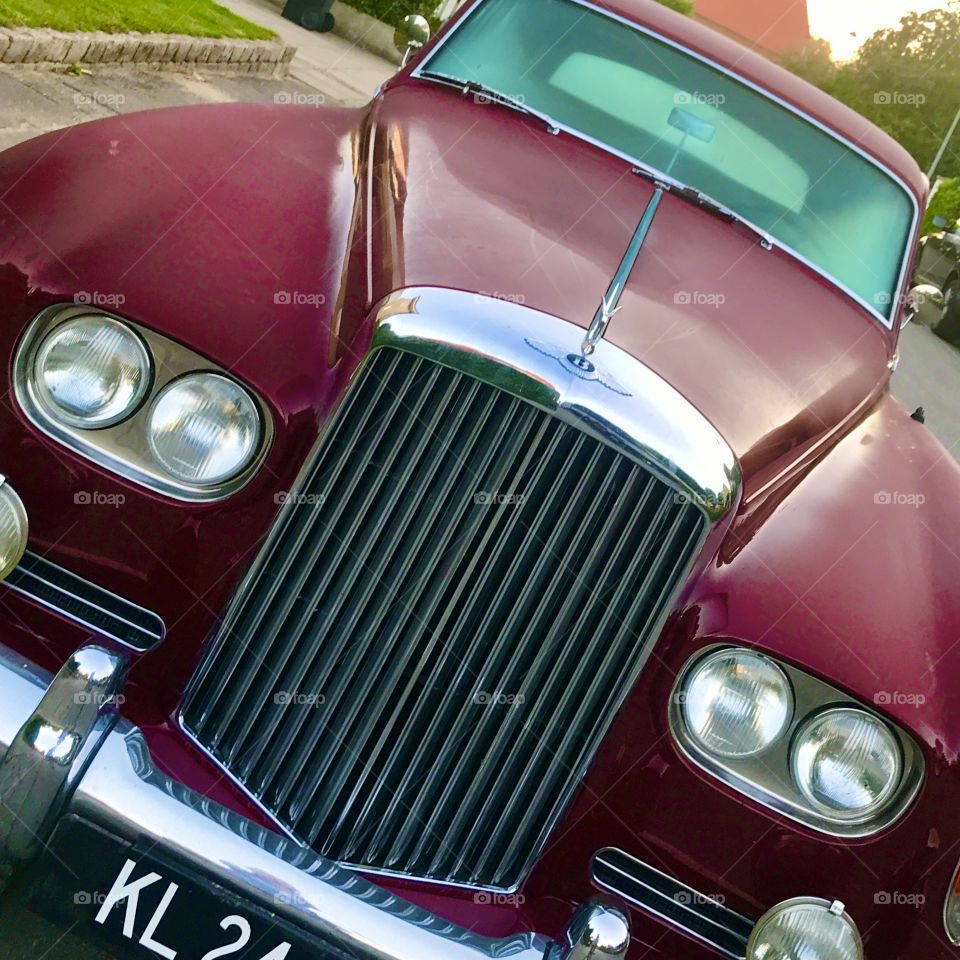 Close-up of aubergine colored Bentley with morning dew. Classic car.
