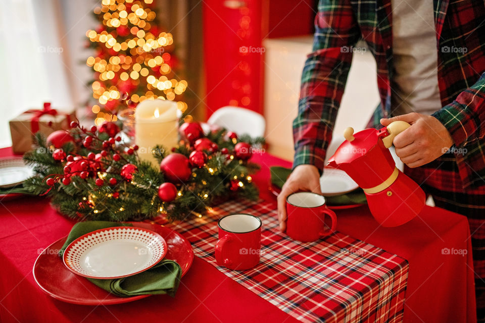 Festive winter cozy kitchen interior with garlands, decorations and gifts.  Christmas dinner at the decorated table.