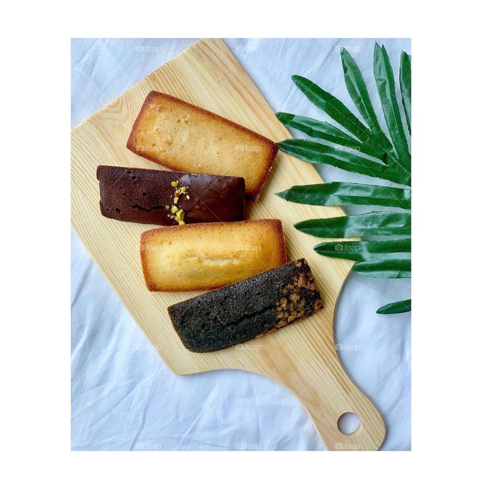 French patisserie financiers in four different flavours - brown butter, dark chocolate, black sesame and yuzu against a natural background