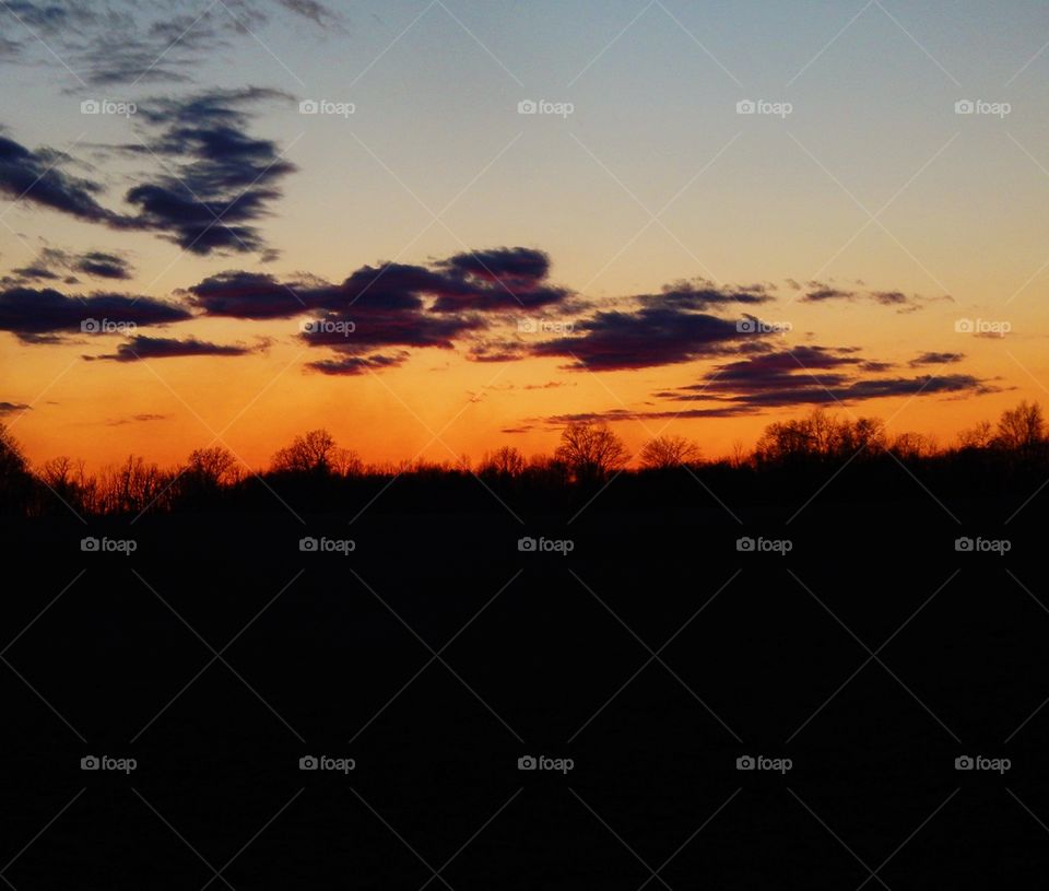 orange sunset over dark field in the country