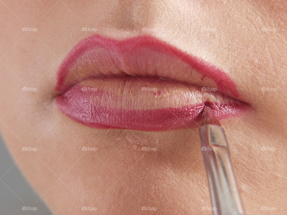 Woman makeup her lips.