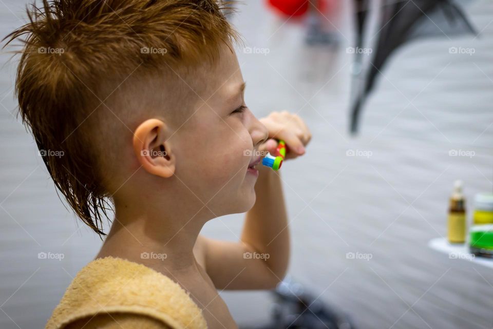 red-haired boy brushes his teeth in the bath, personal hygiene.