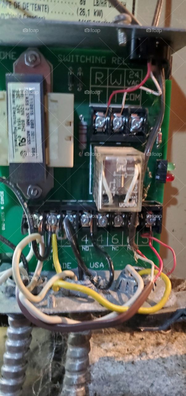Inside of Zone Control for heating system. Colored wires are attached to screws on a green panel. Other parts of control are visible.