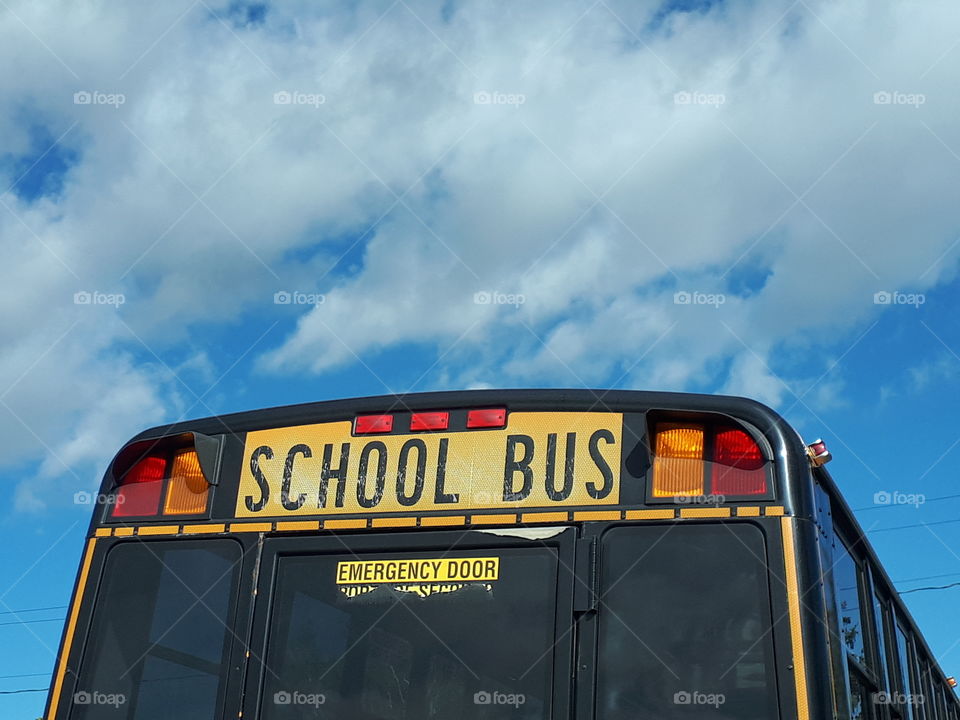 A yellow school bus against the bright blue sky.